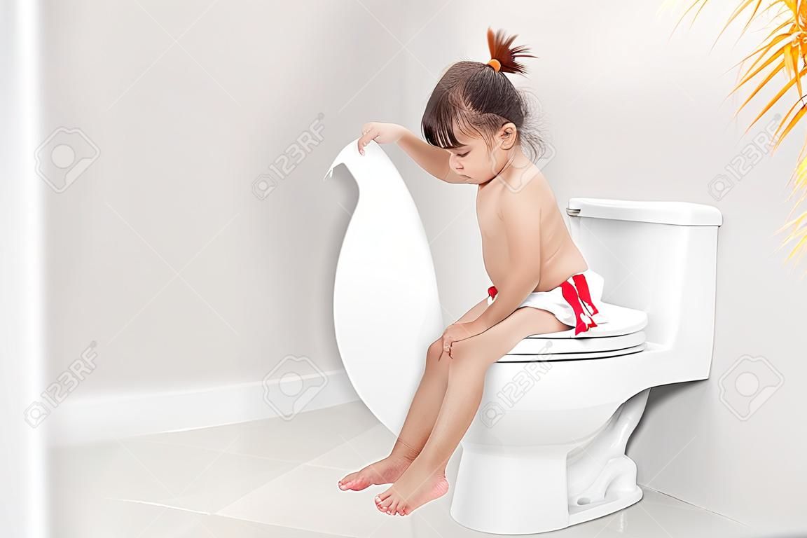 Das kleine Mädchen sitzt auf der Toilette und leidet an Verstopfung oder Hämorrhoiden.