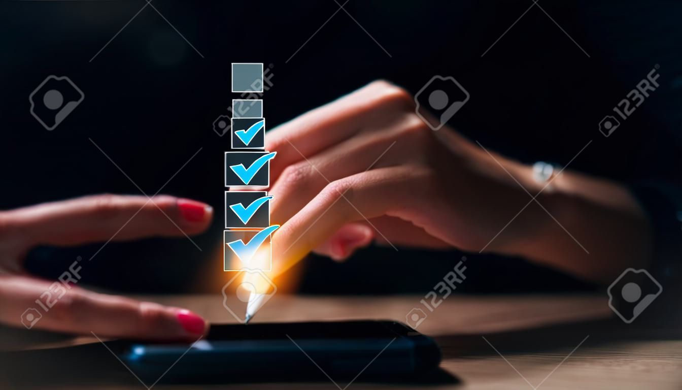 Businesswomen use pens to tick the correct sign mark in the checkbox for the quality document control checklist and the business approves the project concept.