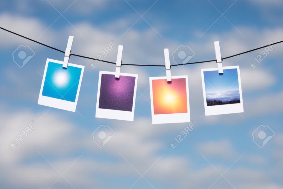 Cierre de fotos instantáneas en blanco secado sobre la ropa sobre fondo de cielo