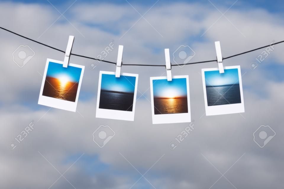 Close up of blank instant photos drying on the clothesline over sky background