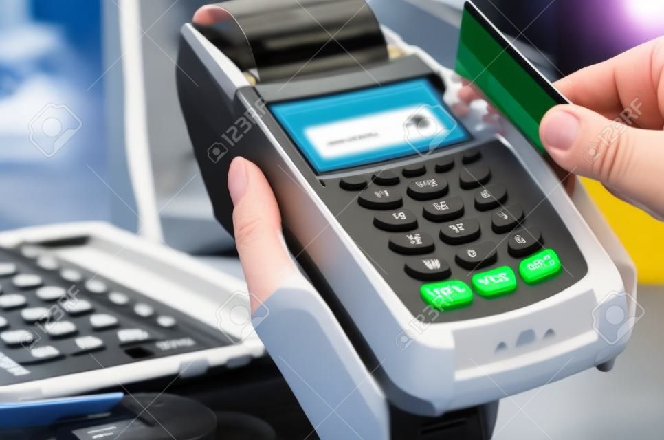 Hand of woman using payment terminal in an electrical shop, paying with credit card, credit card reader, finance concept