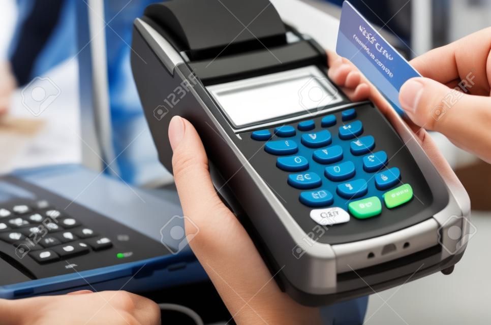 Mano de la mujer con el terminal de pago en una tienda de electrónica, pagando con tarjeta de crédito, lector de tarjetas de crédito, el concepto de finanzas