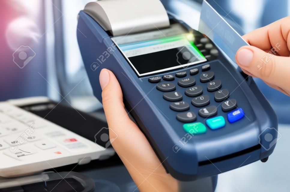 Mano de la mujer con el terminal de pago en una tienda de electrónica, pagando con tarjeta de crédito, lector de tarjetas de crédito, el concepto de finanzas