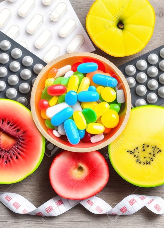 Fresh natural fruits, tape measure and medical pills. Slimming and choice between eating fruits and taking supplements for strengthening immunity