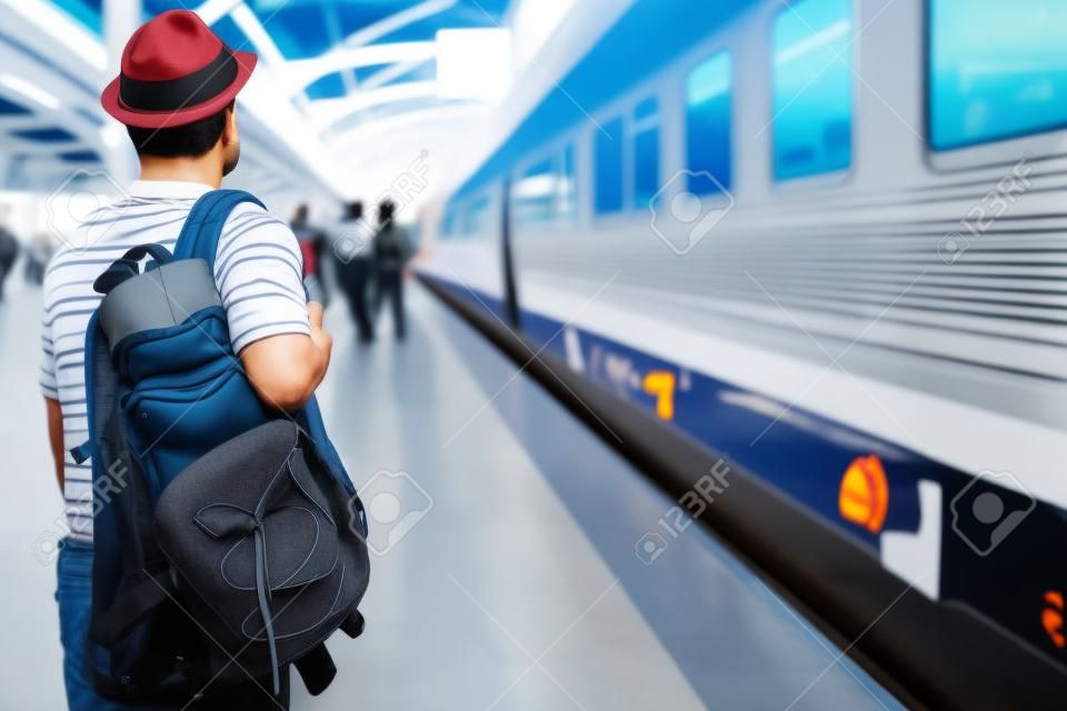 The passengers are stand waiting for the Station platform. Young man traveler with backpack looking waiting for train. the tourist travel Get ready for departure concept.