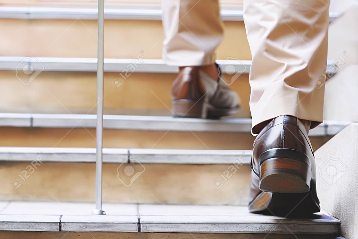 Nowoczesny biznesmen pracujący z bliska nogi chodzące po schodach w nowoczesnym mieście. w godzinach szczytu do pracy w biurze pośpiechu. w pierwszy poranek pracy. klatka schodowa