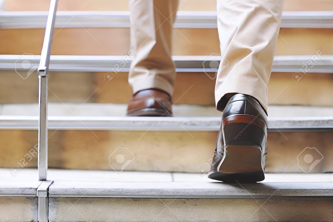 Nowoczesny biznesmen pracujący z bliska nogi chodzące po schodach w nowoczesnym mieście. w godzinach szczytu do pracy w biurze pośpiechu. w pierwszy poranek pracy. klatka schodowa
