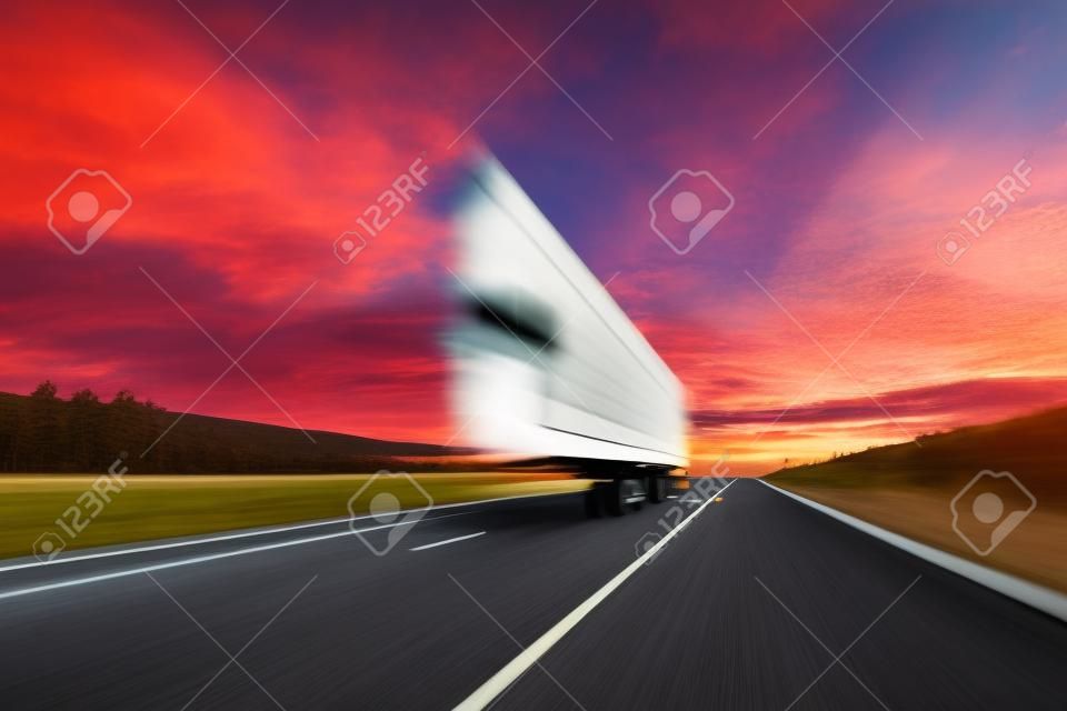 ぼやける。大型トラックが高速道路を高速で走っています。真っ赤な雲のある空。貨物の配達。