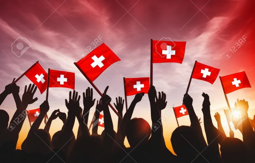 Grupo de personas que ondeaban banderas de Suiza en Contraluz