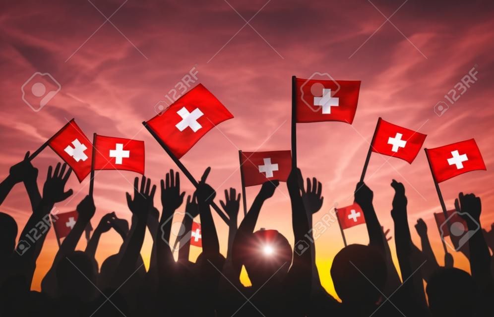 Grupo de personas que ondeaban banderas de Suiza en Contraluz