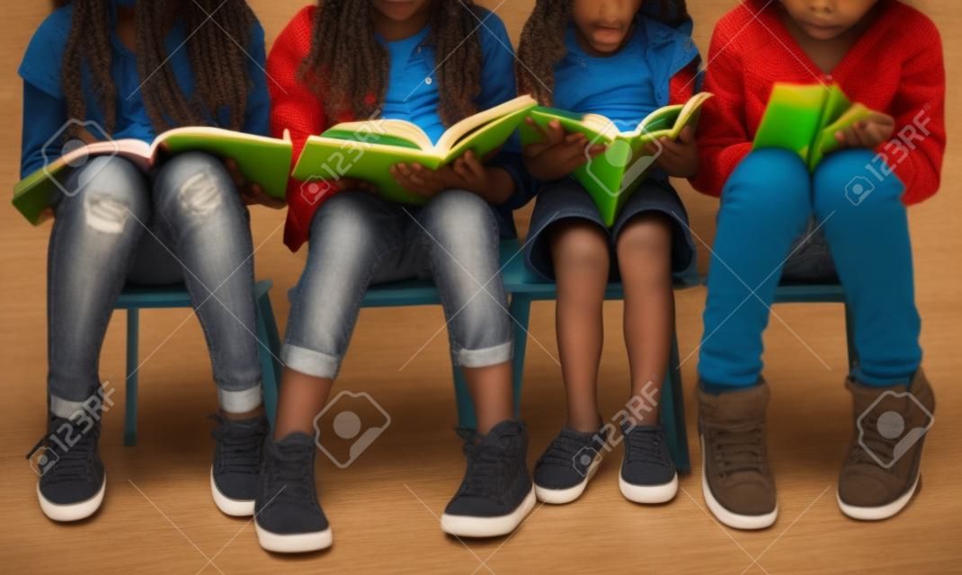 Diverse group of kids sitting in a row reading books