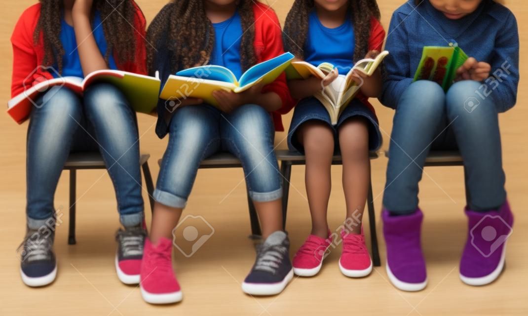 Diverse group of kids sitting in a row reading books