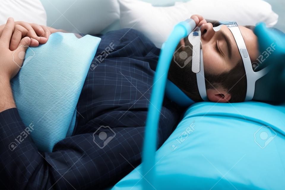 A man sleeping with anti snoring chin strap