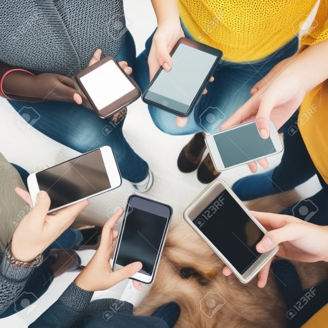 Junge Erwachsene, die Smartphones in einem Kreissocial media und in einem Verbindungskonzept verwenden