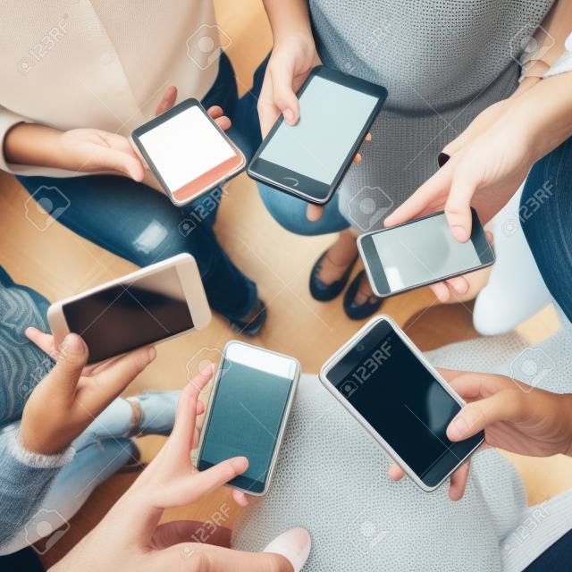 Junge Erwachsene, die Smartphones in einem Kreissocial media und in einem Verbindungskonzept verwenden