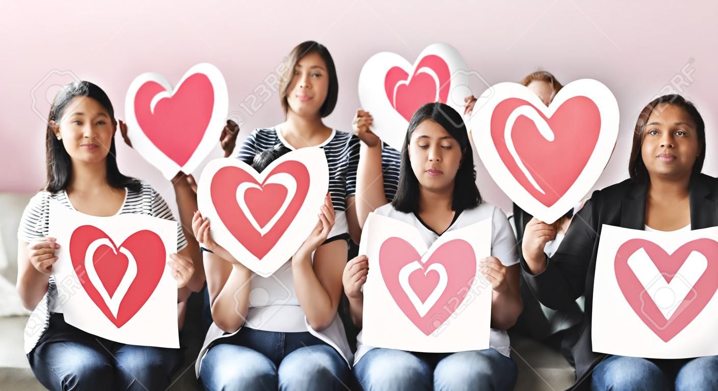 Diverse people holding heart icons