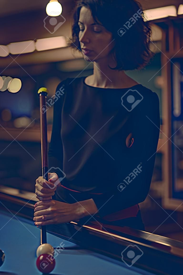 Woman playing pool at a bar
