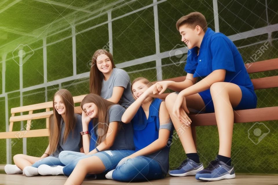 Group of young teenager friends sitting on a bench relaxing