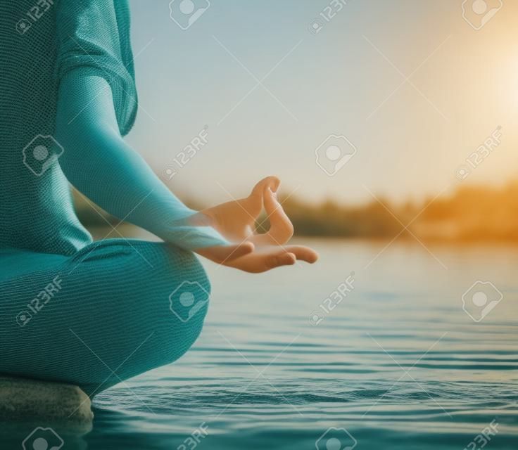 Woman practicing yoga by a lake