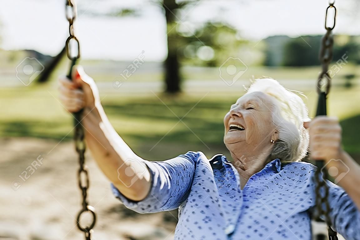 Donna anziana allegra su un'altalena in un parco giochi