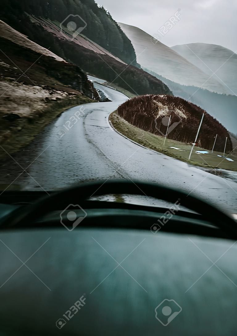 Uomo alla guida di un'auto nelle Highlands, in Scozia