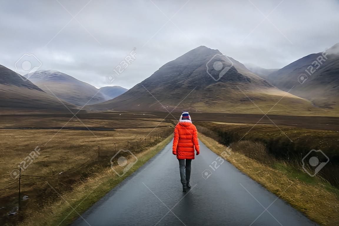 Donna che cammina su una strada a Glen Etive, Scozia
