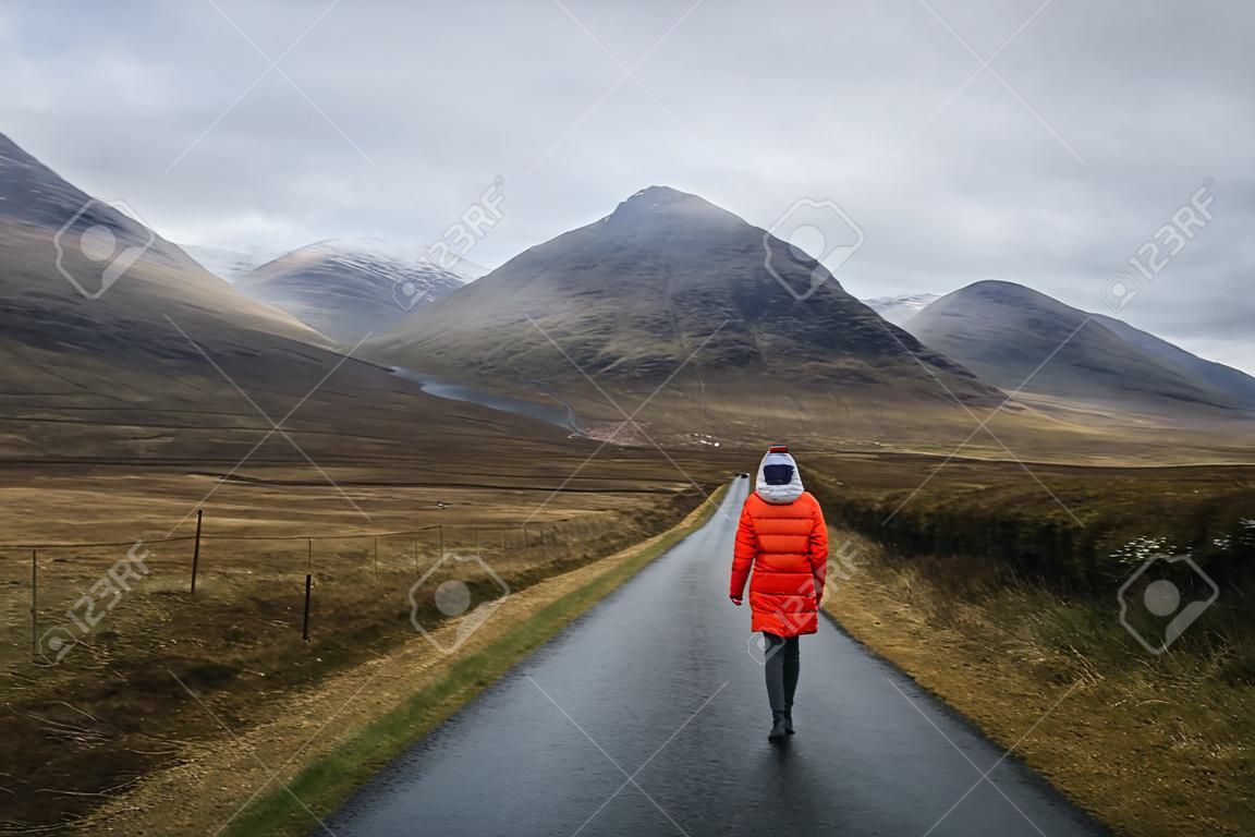 Mulher que anda em uma estrada em Glen Etive, Scotland