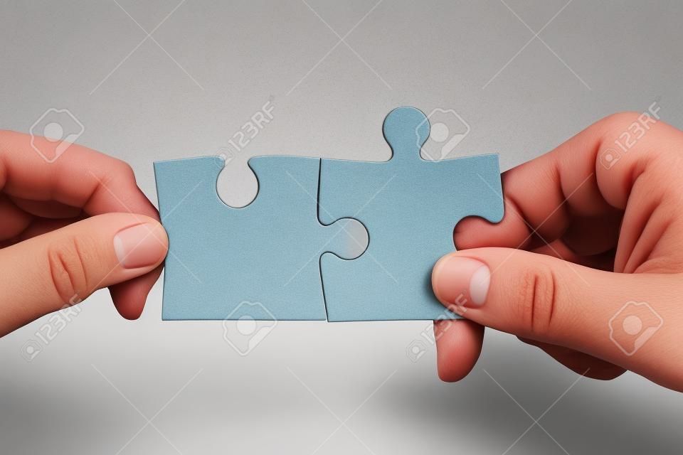 Due mani che tengono i pezzi del puzzle e di collegarli