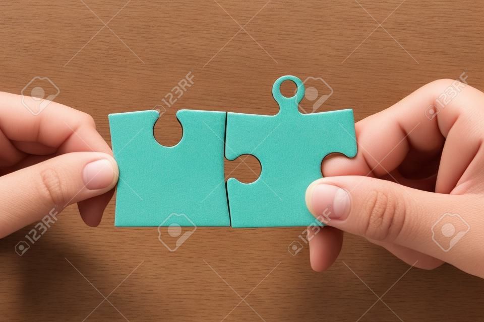 Due mani che tengono i pezzi del puzzle e di collegarli