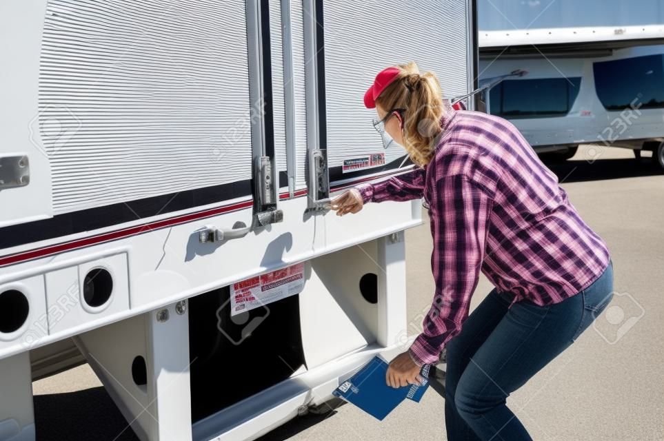 Woman truck driver checking her trailer seal number to make sure it matches the numbers on her bill of lading.