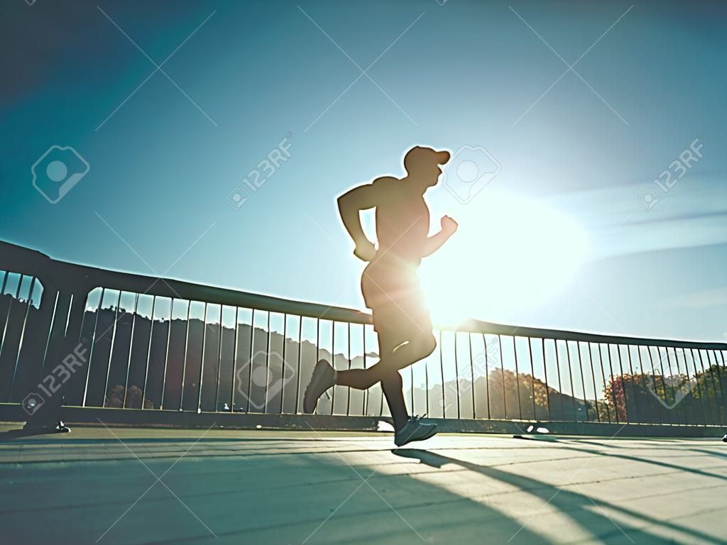 Sportieve man rennen op de brug. Sport en lifestyle concept - slanke man die over de stadsbrug. Runner werken buiten
