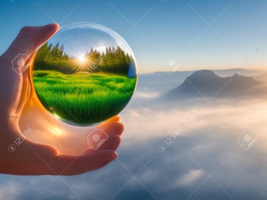 Prachtig landschap van het Saksen Nationaal Park in Duitsland reflecterend in een grote glazen bal in mannelijke vingers