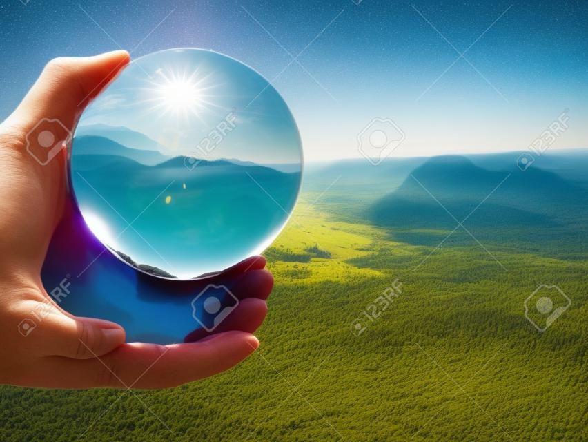 Stunning landscape of the Saxony National Park in Germany reflecting in a large glass ball in male hand fingers