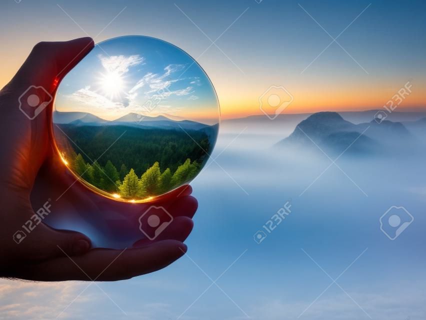 Stunning landscape of the Saxony National Park in Germany reflecting in a large glass ball in male hand fingers