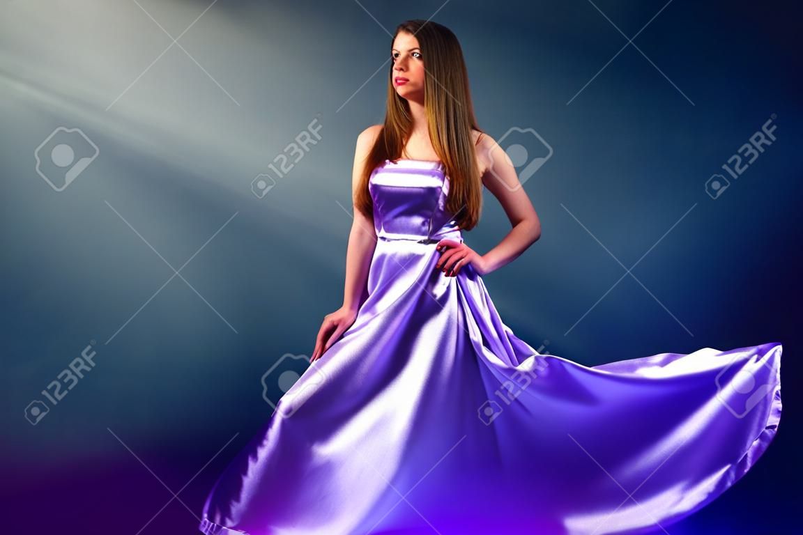 Belle fille en robe longue violette sur fond noir