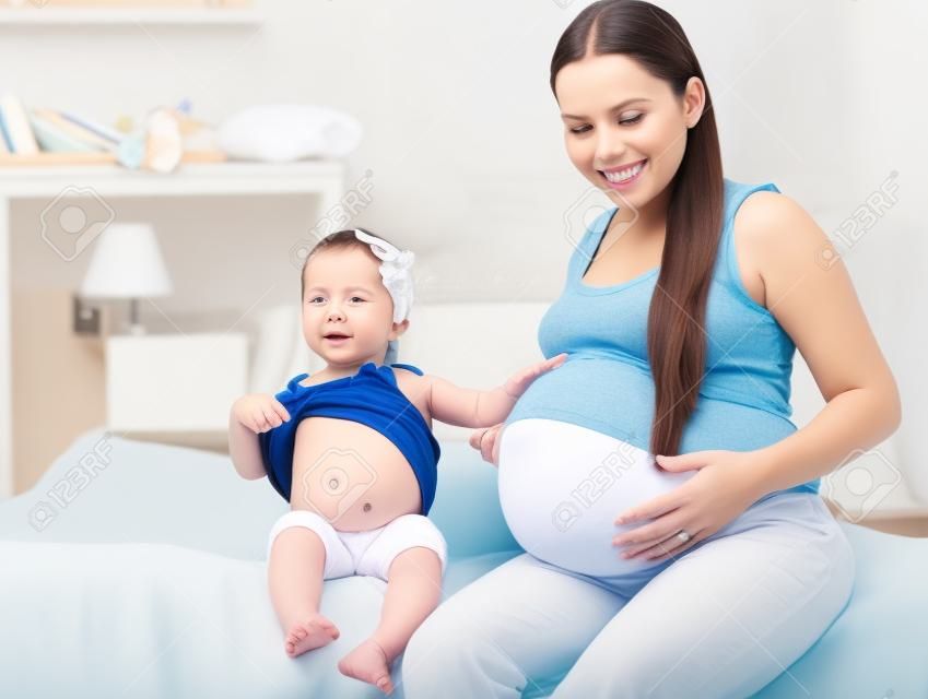 madre e la sua bambina in attesa di pancia neonato e mostrando (concentrarsi sul bambino ragazza)