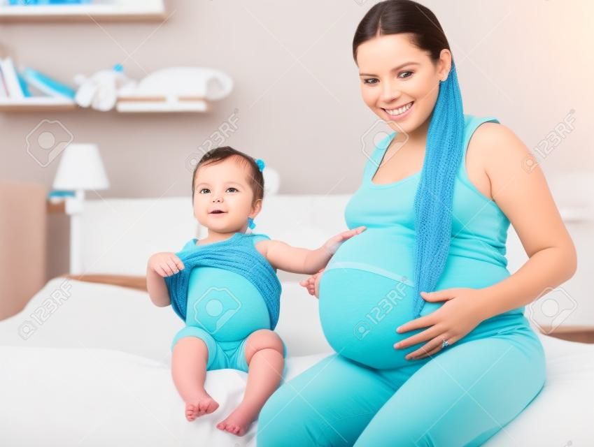 madre e la sua bambina in attesa di pancia neonato e mostrando (concentrarsi sul bambino ragazza)