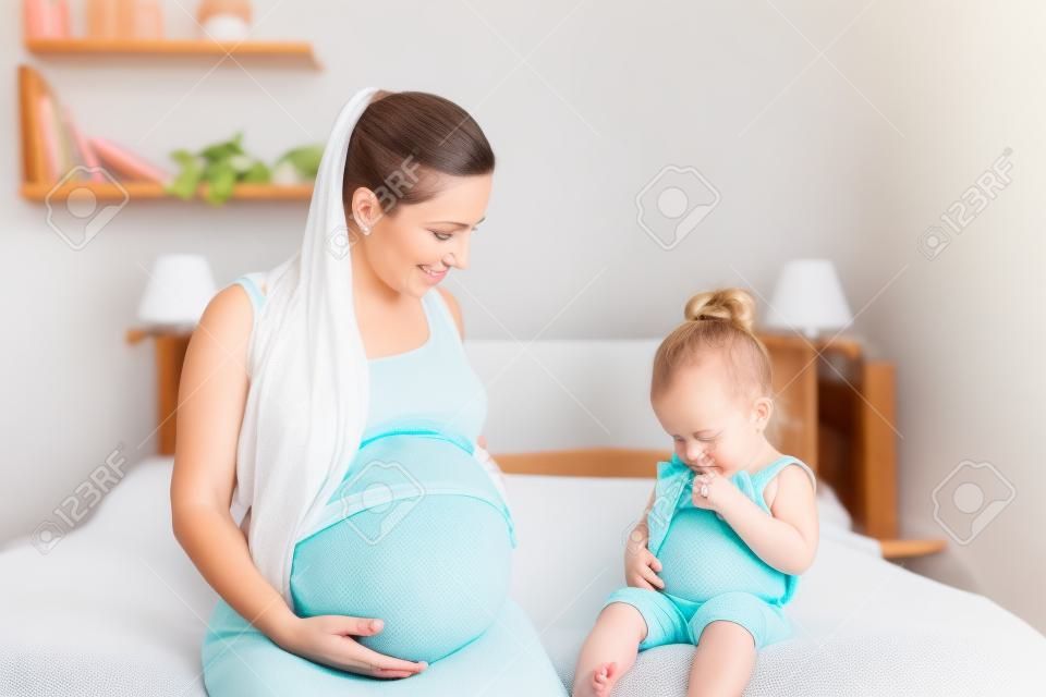 母と彼女の赤ん坊の娘の新生児のため待っているとお腹 （女の赤ちゃんにフォーカス） を示す