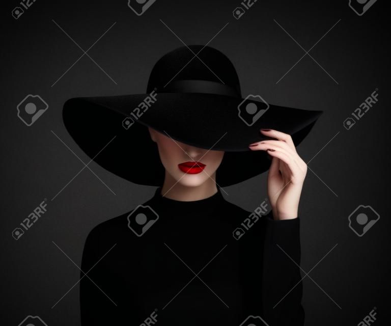 Luksusowe kobieta w dużym czarnym kapeluszu i jasne usta na czarnym tle