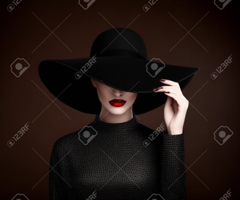 Роскошная женщина в большой черной шляпе и яркие губы на черном фоне