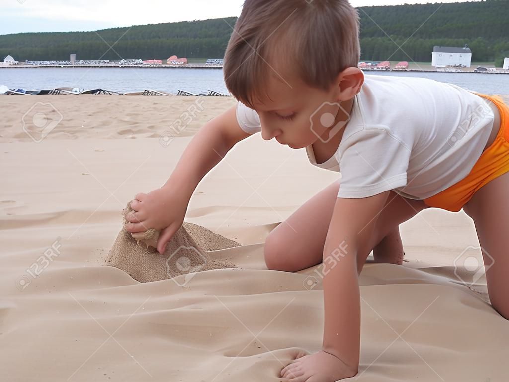 Boy plays with sand at the beach