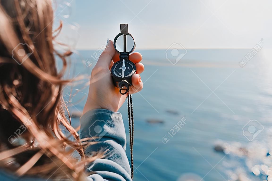 Donna viaggiatore alla ricerca direzione con una bussola sulla costa, vicino al mare in estate