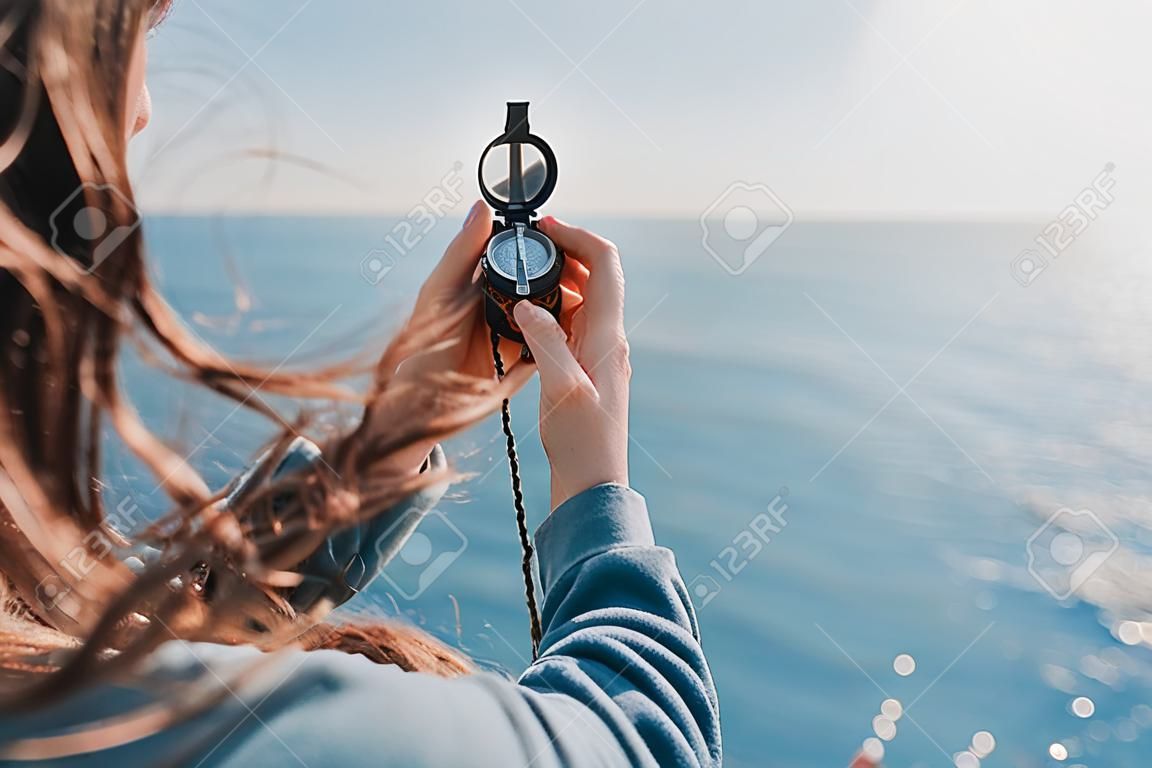 Mujer viajero en busca de dirección con una brújula en la costa cerca del mar en verano