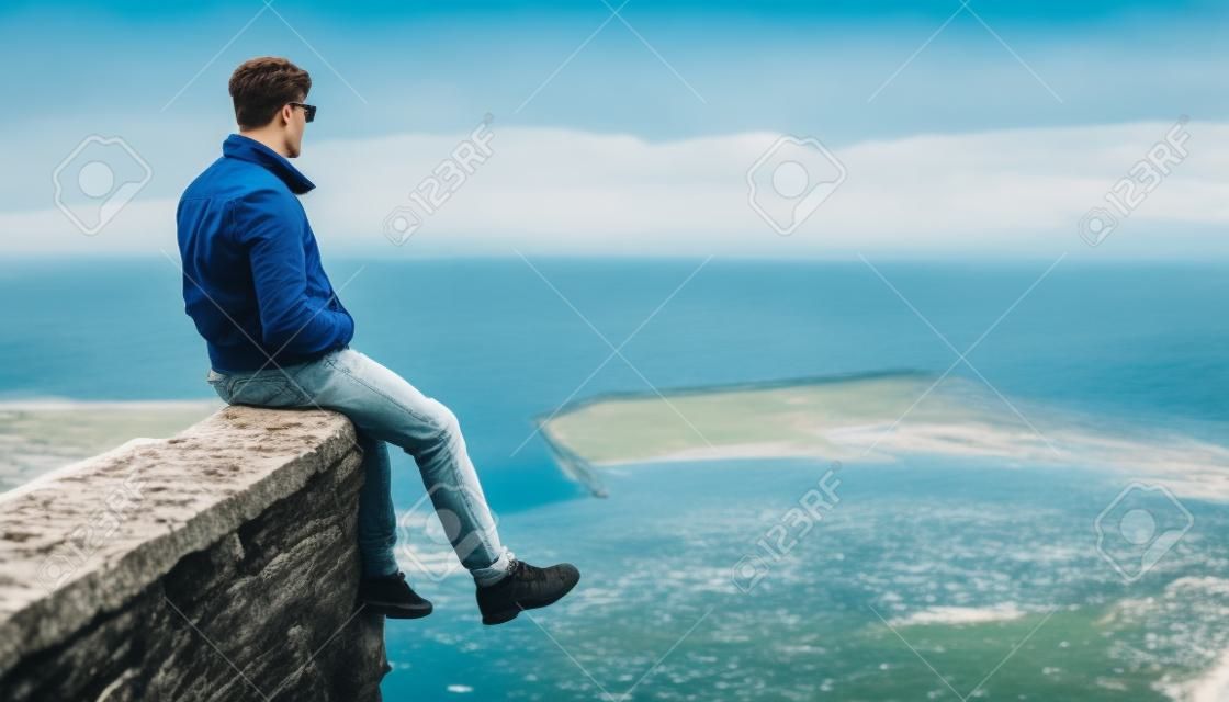 Young man sitting over the sea bay and enjoying view of nature