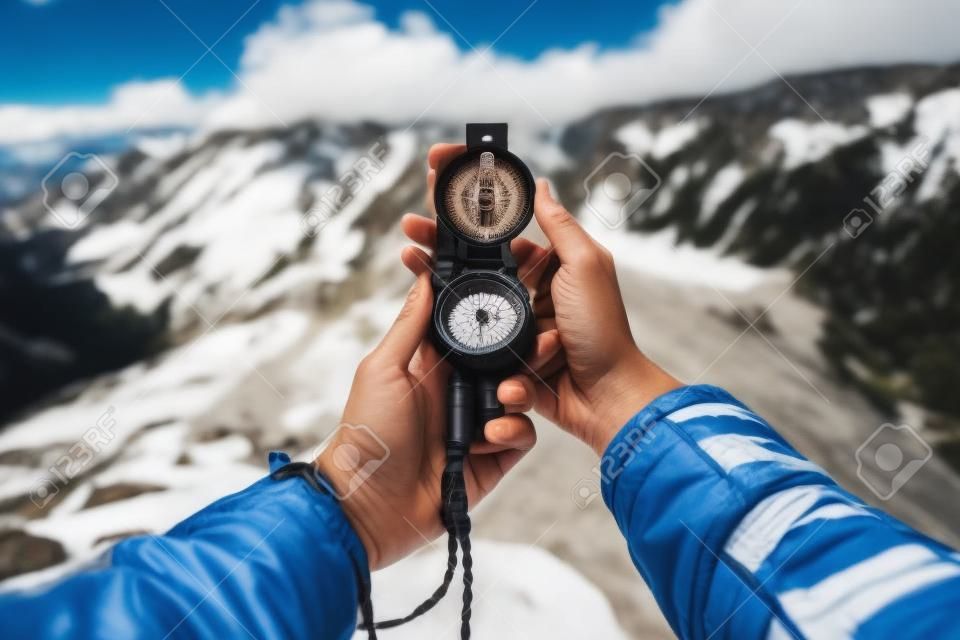 Female traveler searching direction with a compass in the mountains. Point of view shot