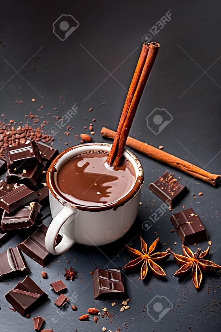 Cup of hot chocolate and pieces of chocolat on dark concrete background