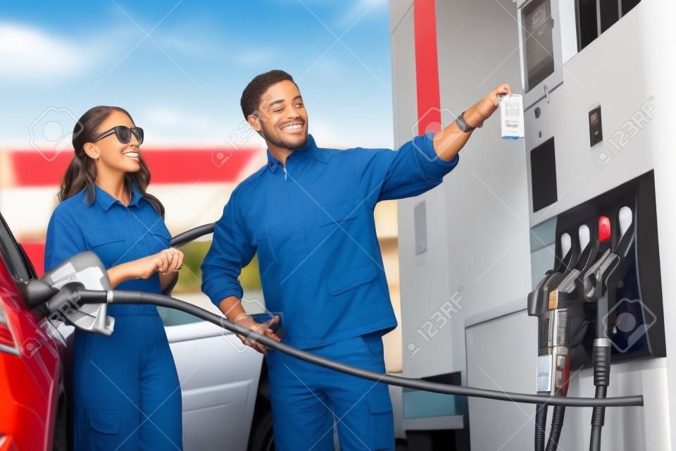 ガソリンスタンドで車に給油ガソリンスタンド労働者と若い女性クライアント