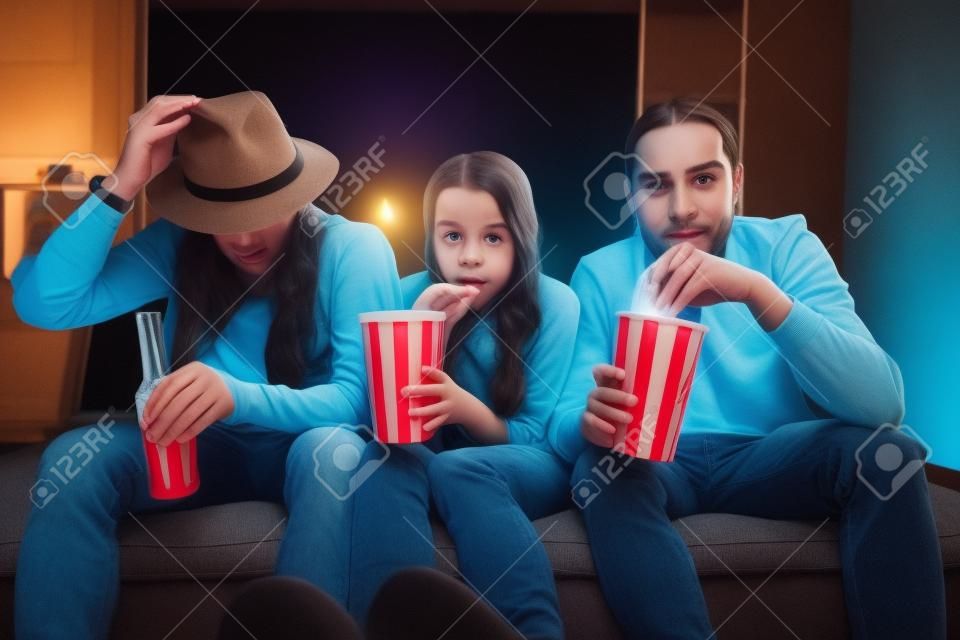 Jonge vrienden kijken enge film, zitten samen met popcornes op de bank thuis
