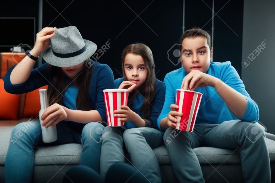 Jonge vrienden kijken enge film, zitten samen met popcornes op de bank thuis