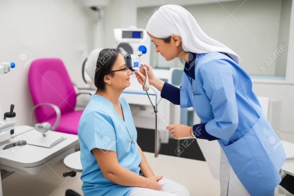 Augenärztin, die den Augendruck mit einem modernen Tonometer bei einer älteren Patientin in der Arztpraxis misst